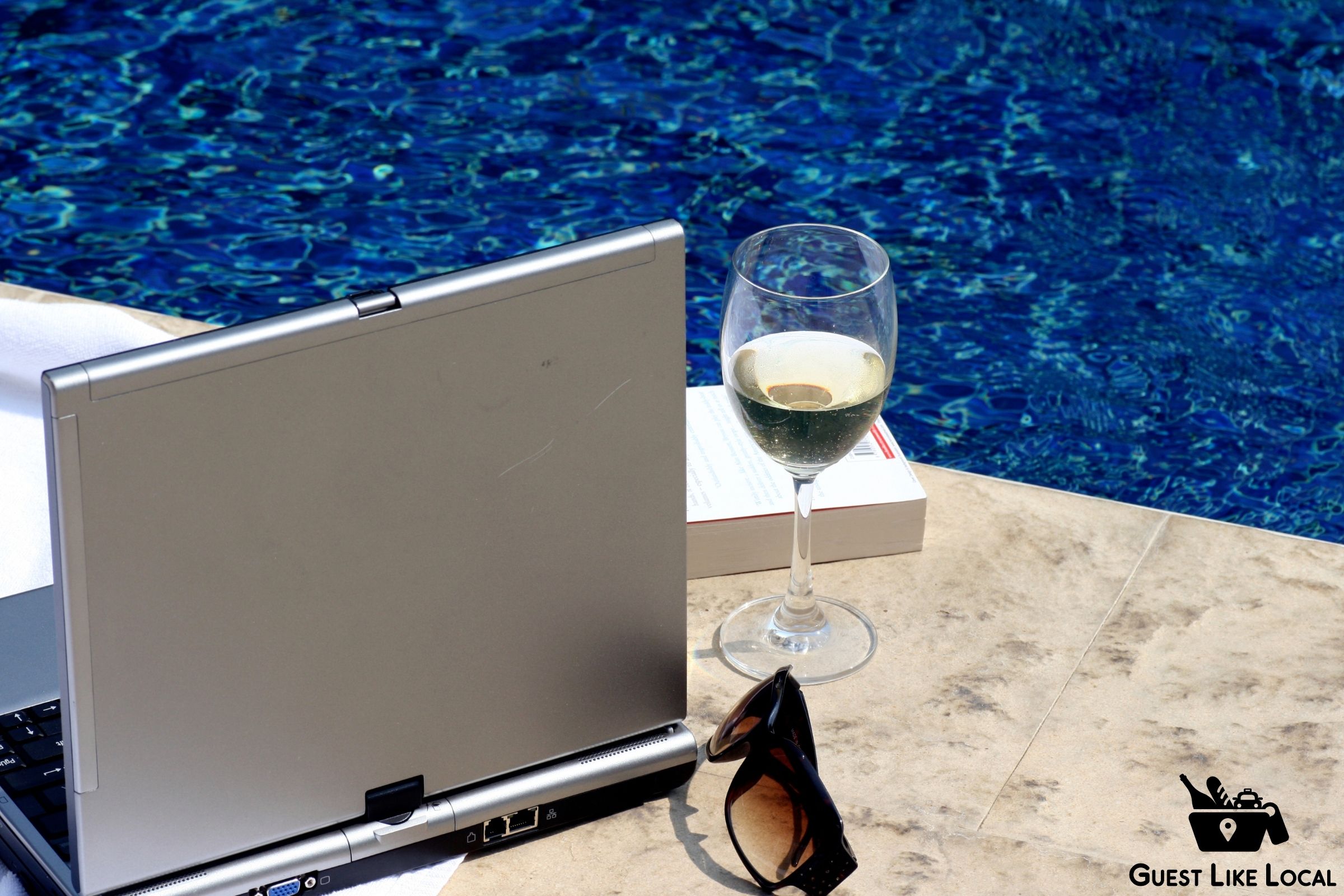 Laptop and glass of wine next to the pool